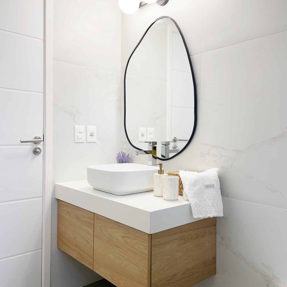 Descubre el baño principal diseñado por Estudio Welfare en José Ignacio, Maldonado. Este espacio se distingue por su luminosidad y estilo contemporáneo, destacando una mesada de cuarzo blanco y detalles en negro para un contraste elegante. La bacha de sobreponer de losa blanca y el espejo con marco negro añaden un toque de sofisticación. La cerámica con vetas beige y bronce claro, similar a un calacatta gold claro, envuelve las paredes, creando una sensación de amplitud y luminosidad. Además, el bajo mesada en maderado claro aporta calidez y un toque de naturaleza al ambiente, ideal para un baño contemporáneo en la playa. En Estudio Welfare, combinamos funcionalidad y estética para crear espacios acogedores y sofisticados.