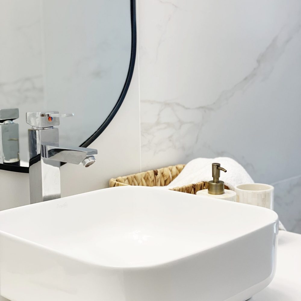 Descubre el baño principal diseñado por Estudio Welfare en José Ignacio, Maldonado. Este espacio se distingue por su luminosidad y estilo contemporáneo, destacando una mesada de cuarzo blanco y detalles en negro para un contraste elegante. La bacha de sobreponer de losa blanca y el espejo con marco negro añaden un toque de sofisticación. La cerámica con vetas beige y bronce claro, similar a un calacatta gold claro, envuelve las paredes, creando una sensación de amplitud y luminosidad. Además, el bajo mesada en maderado claro aporta calidez y un toque de naturaleza al ambiente, ideal para un baño contemporáneo en la playa. En Estudio Welfare, combinamos funcionalidad y estética para crear espacios acogedores y sofisticados.