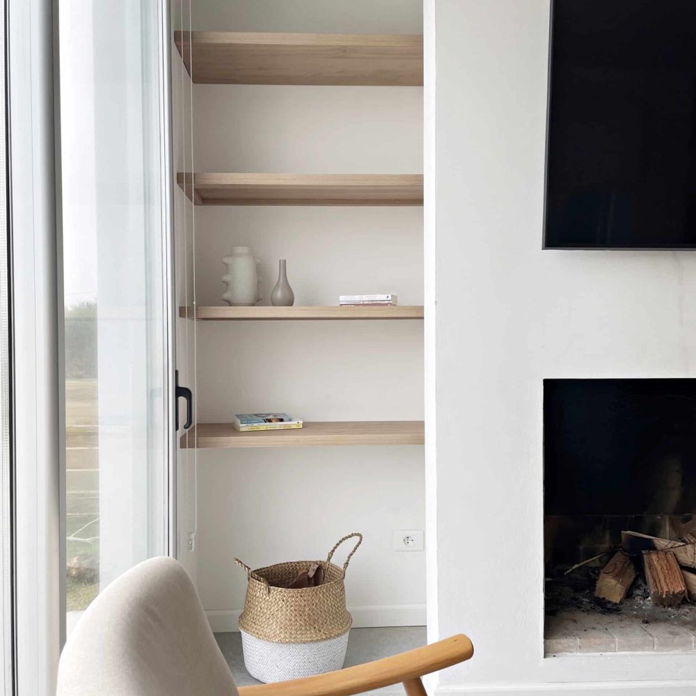 Descubre la elegancia relajada de nuestra sala de estar en esta casa introspectiva con vista a la piscina en la zona de playas de José Ignacio. Este espacio, que incorpora un comedor, se caracteriza por su diseño funcional y acogedor. Un mueble multifuncional de 5 metros sirve como aparador para el comedor y como escritorio, albergando incluso una enfriadora de vinos para añadir un toque de sofisticación. El centro de atención de la sala es un cómodo sofá chaise en forma de L con una funda de tussor, acompañado de una butaca complementaria para mayor comodidad. Las cortinas de lino suavizan la luz natural, creando un ambiente sereno y acogedor perfecto para relajarse y disfrutar de la vista al aire libre.