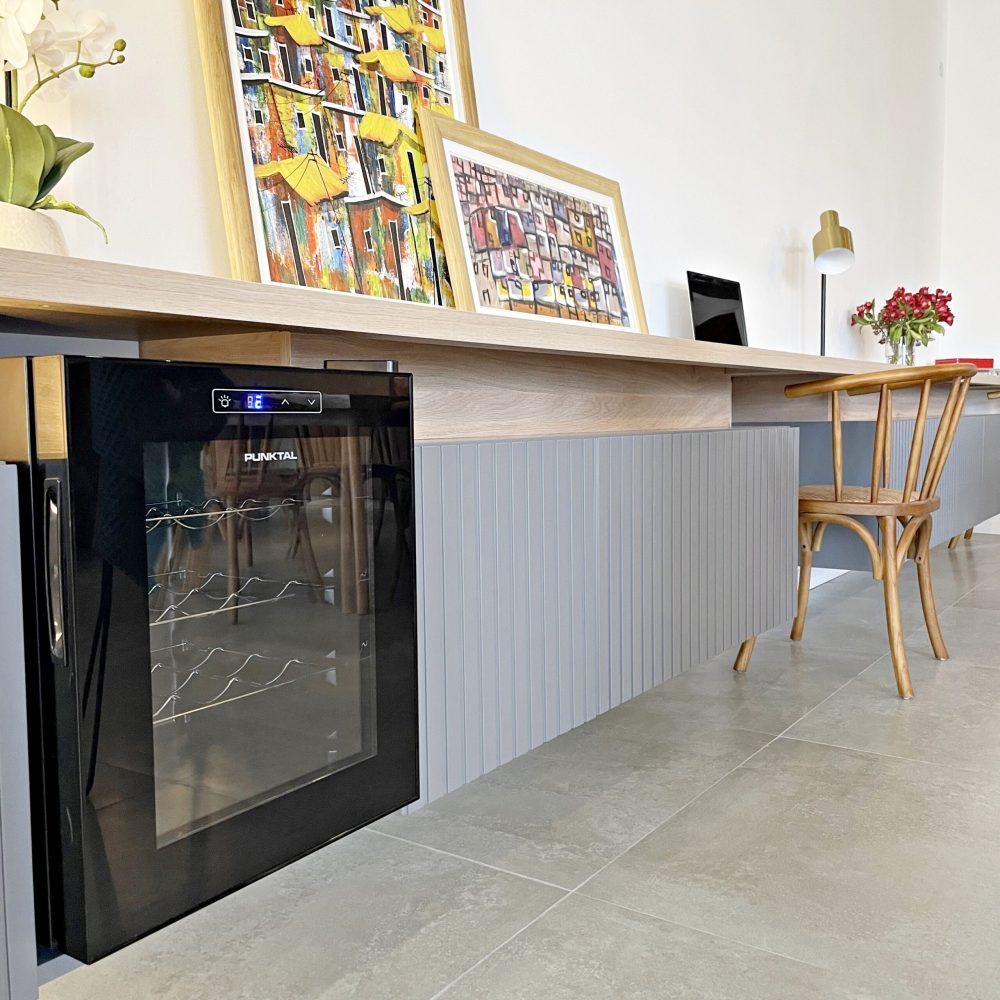 Descubre la elegancia relajada de nuestra sala de estar en esta casa introspectiva con vista a la piscina en la zona de playas de José Ignacio. Este espacio, que incorpora un comedor, se caracteriza por su diseño funcional y acogedor. Un mueble multifuncional de 5 metros sirve como aparador para el comedor y como escritorio, albergando incluso una enfriadora de vinos para añadir un toque de sofisticación. El centro de atención de la sala es un cómodo sofá chaise en forma de L con una funda de tussor, acompañado de una butaca complementaria para mayor comodidad. Las cortinas de lino suavizan la luz natural, creando un ambiente sereno y acogedor perfecto para relajarse y disfrutar de la vista al aire libre.