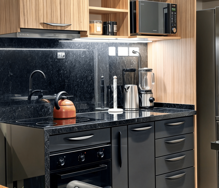 Proyecto de diseño de cocina en Haras del Lago, un barrio cerrado en Canelones, Uruguay. La cocina presenta muebles en acabado maderado, un tablero negro antihuella y mesadas de granito negro absoluto, combinando elegancia y funcionalidad.