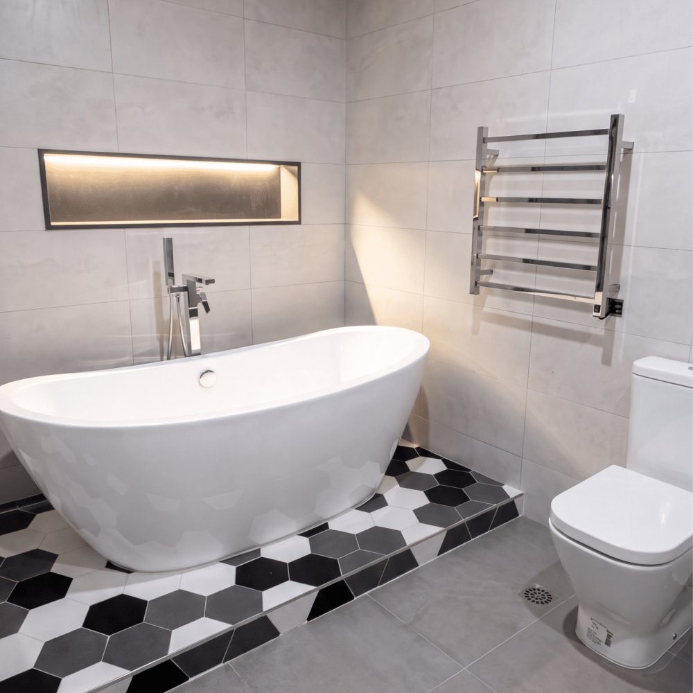 Diseño de baño contemporáneo en Altos de La Tahona, con bañera exenta, ducha vidriada, mueble de madera y revestimiento hexagonal en blanco, gris y negro.